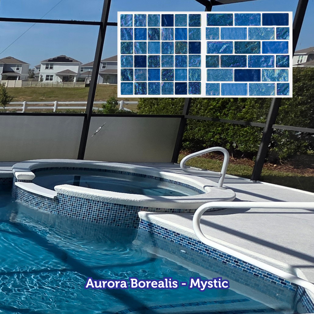 Pool with blue mosaic tile, white trim, and a hot tub. Blue water, outdoor setting, with houses visible.