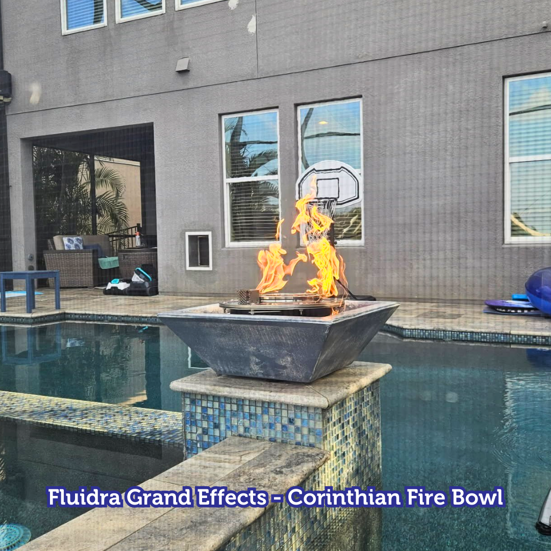 Fire bowl with flames sits beside a pool. House in background with basketball hoop visible.