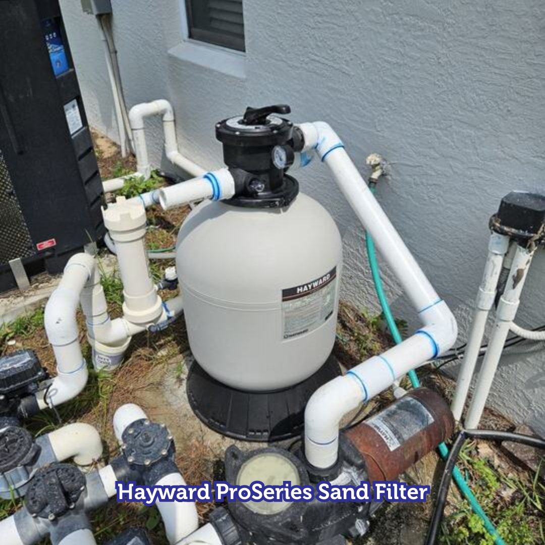 Hayward ProSeries sand filter, white tank with black top and piping, outdoors near a pool.