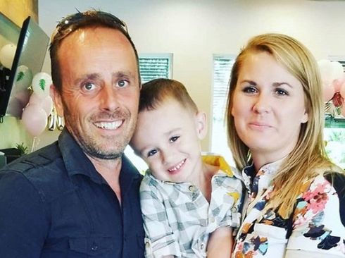 A man and a woman are holding a little boy in their arms.
