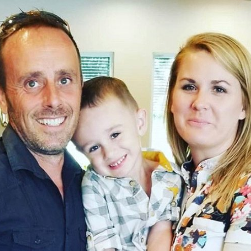 A man and a woman are holding a little boy in their arms.