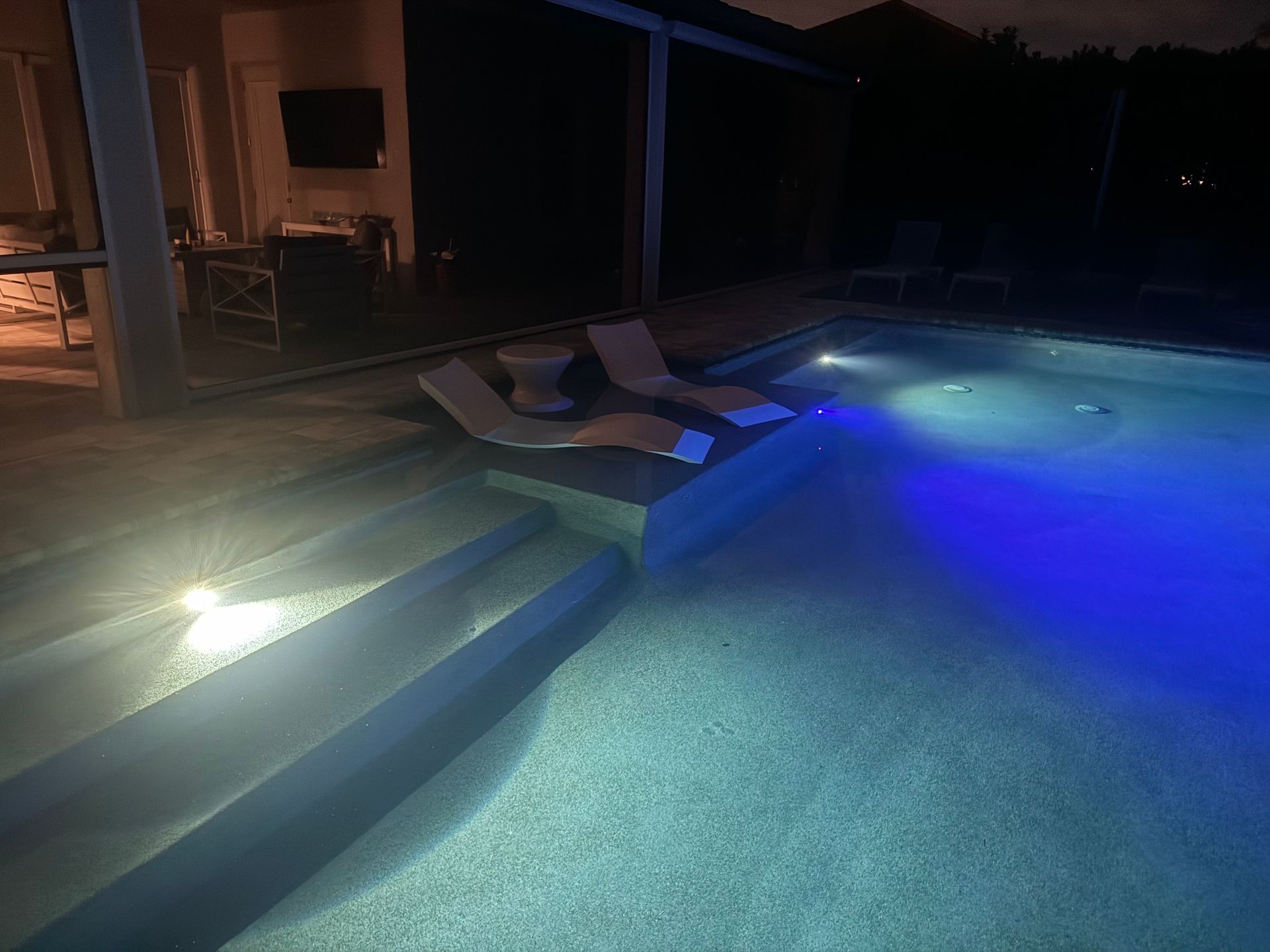 A swimming pool is lit up at night with blue lights