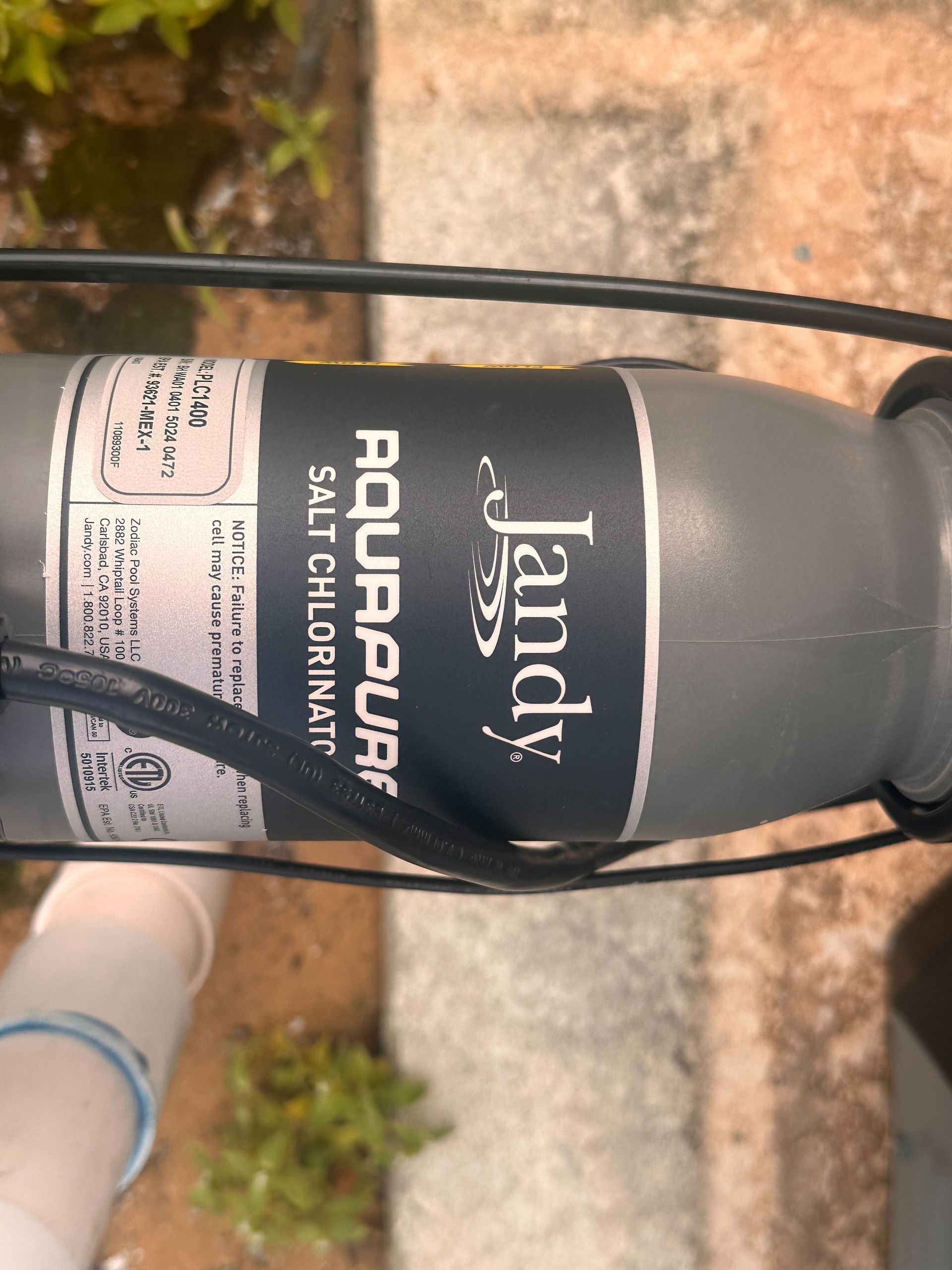 Close-up of a gray Jandy AquaPure salt chlorinator label and connecting wires.