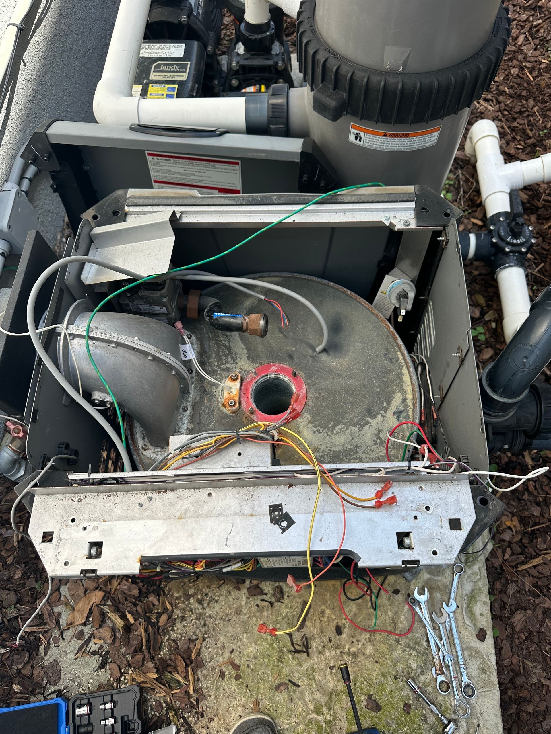 A swimming pool filter is being repaired with a lot of wires coming out of it.