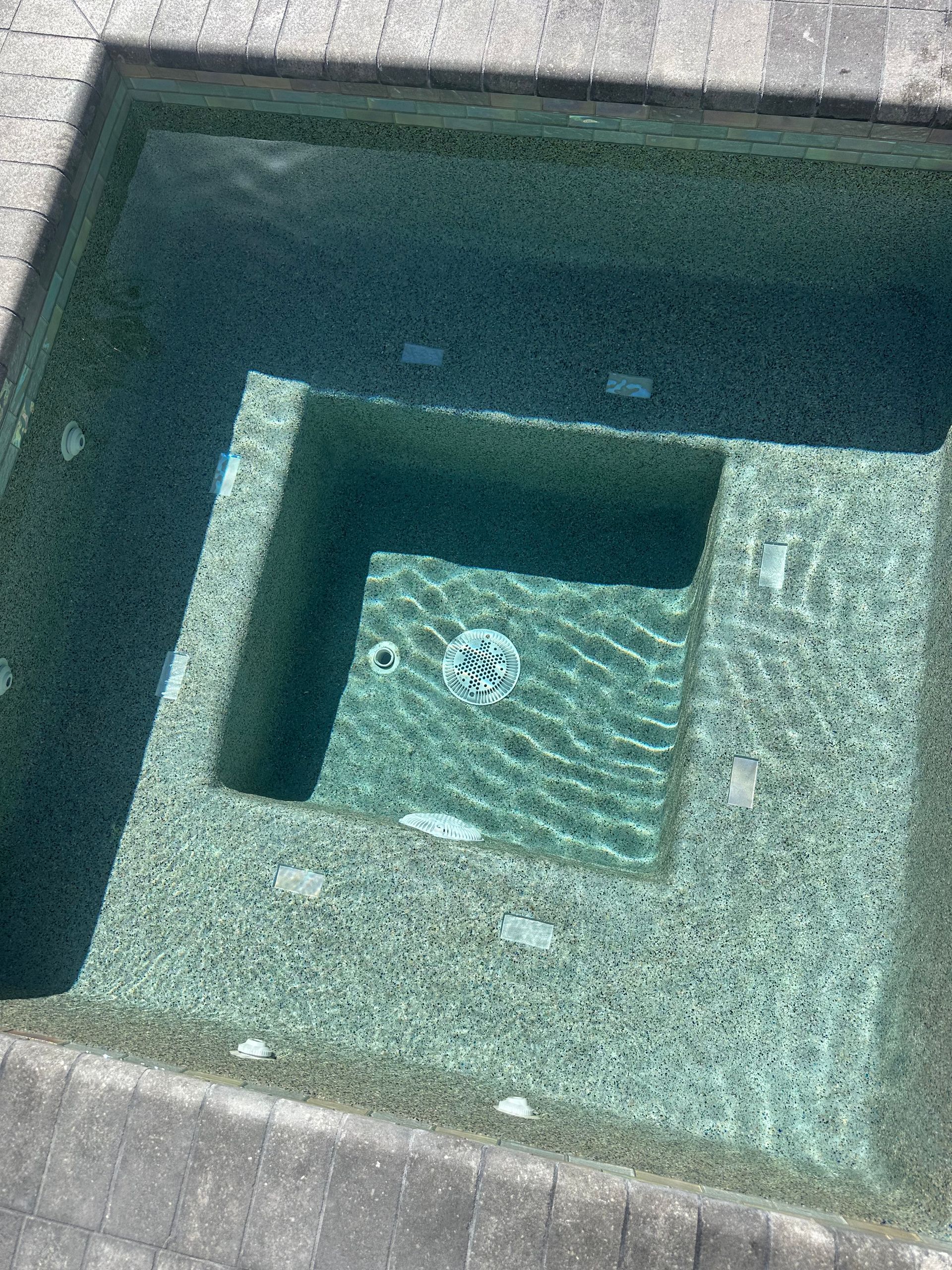 Swimming pool with steps, textured turquoise tile, and clear water.