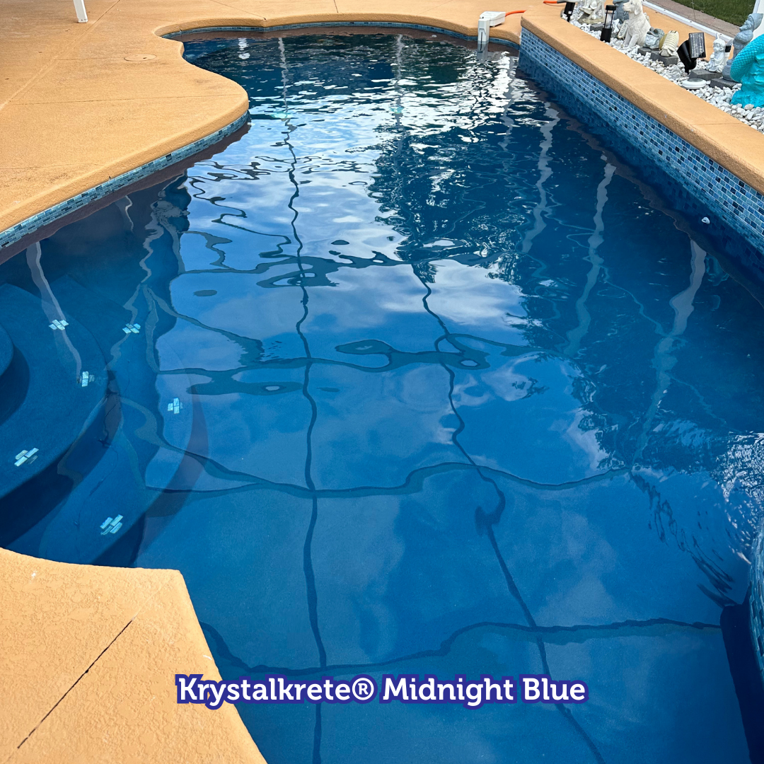 Swimming pool with dark blue water and light brown surrounding deck.