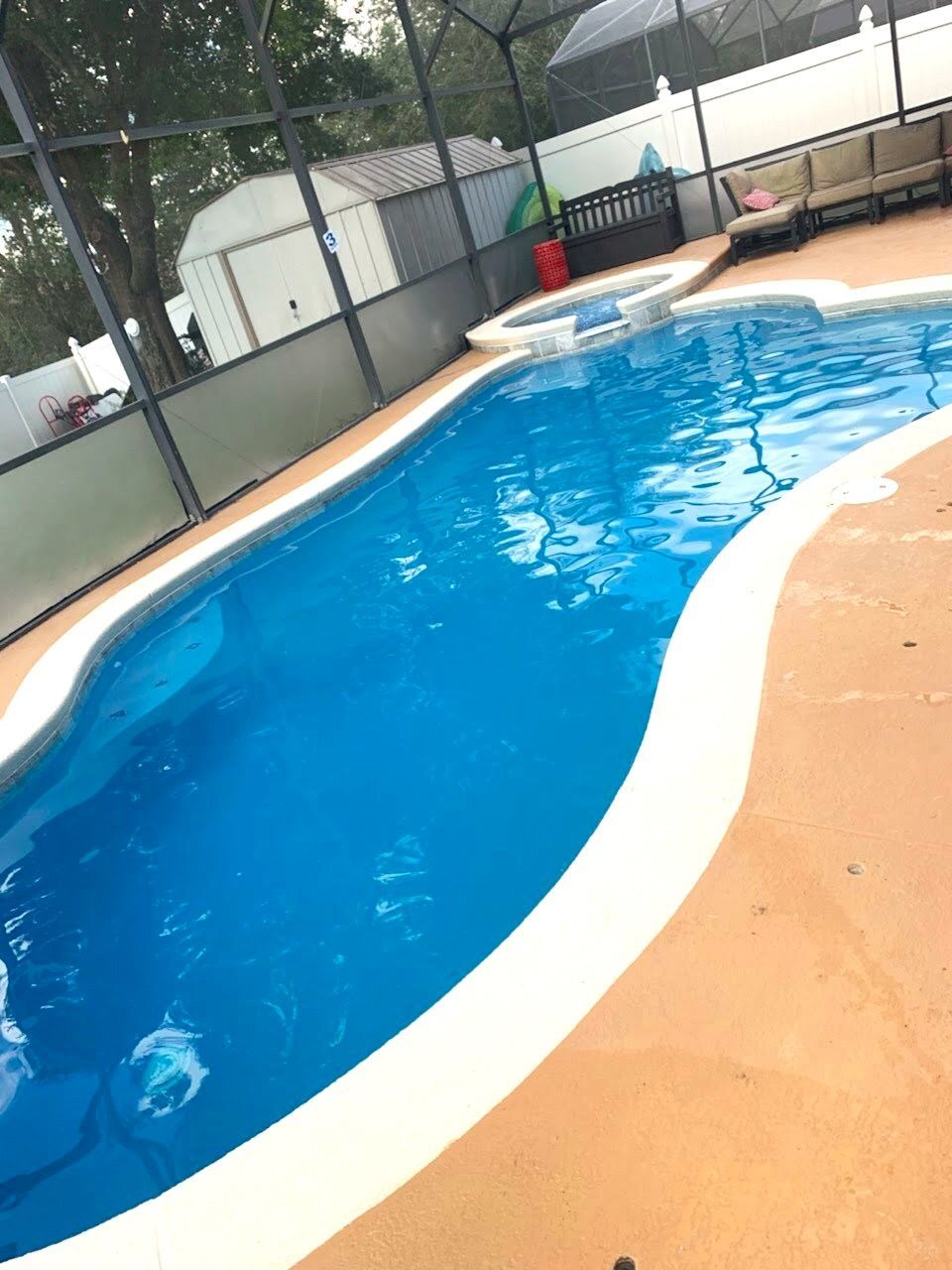 A large swimming pool is surrounded by a screened in area