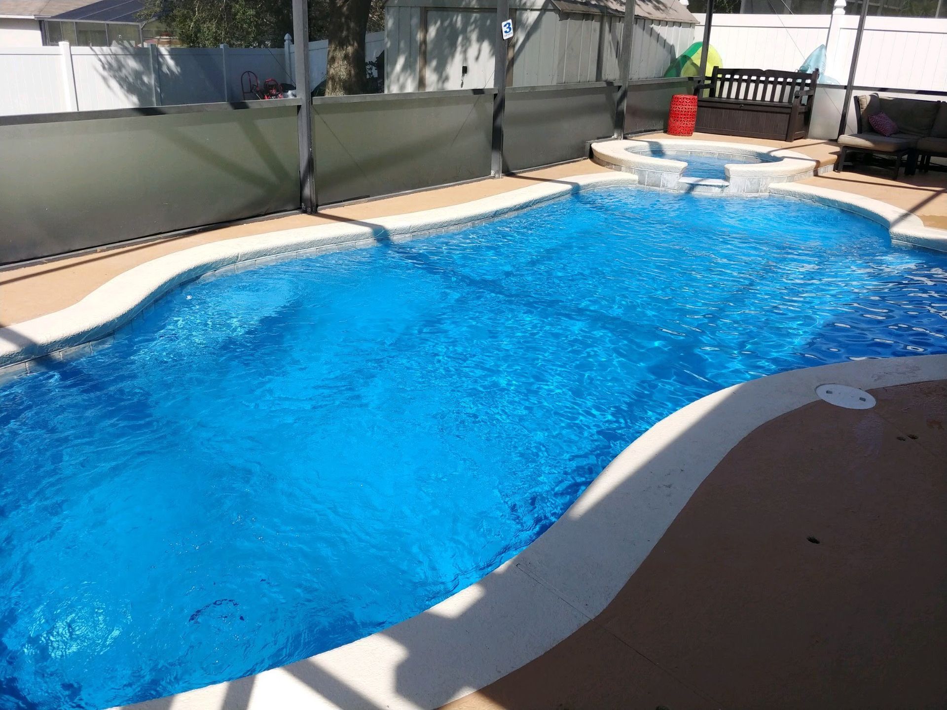 A large blue swimming pool with a bench in the background