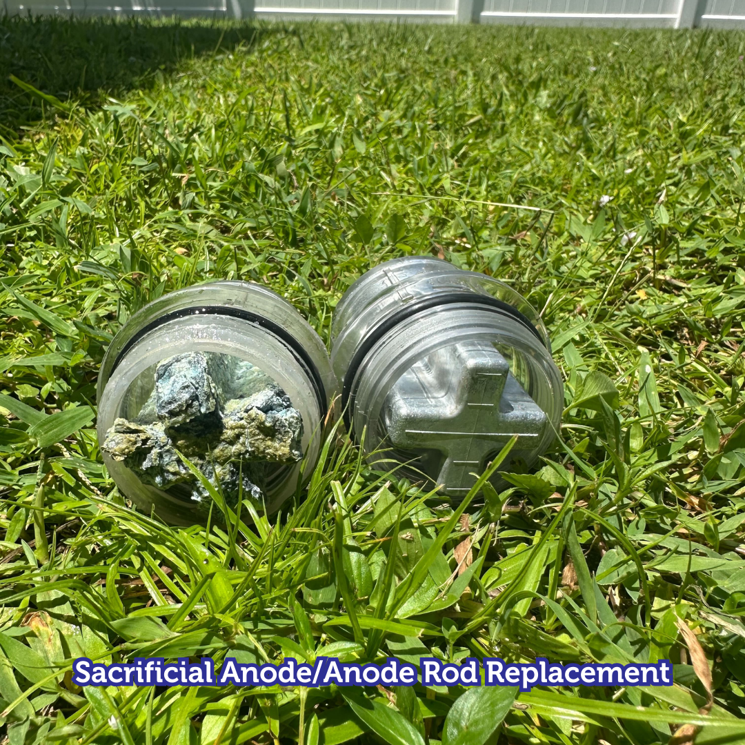 Two water heater anodes, one corroded, in grass, labeled 