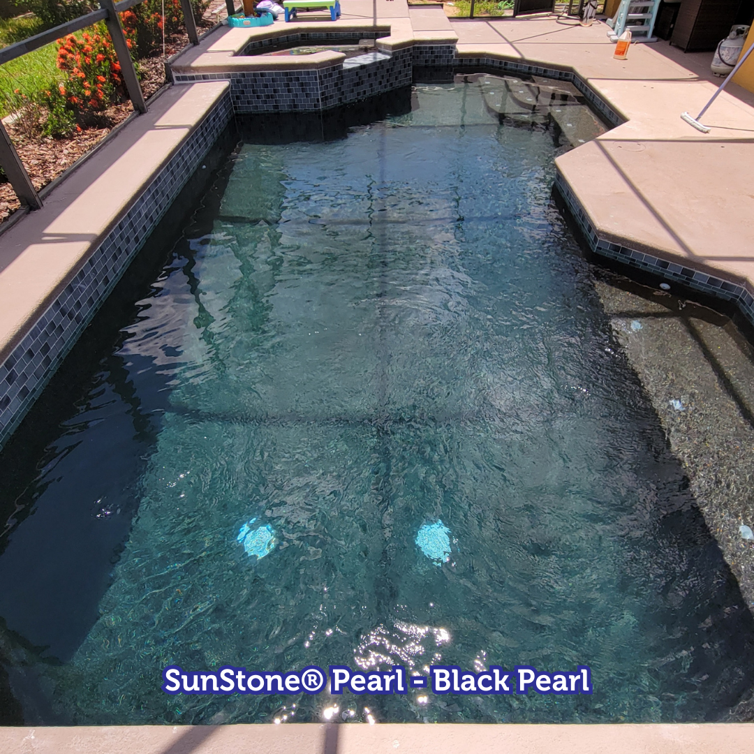 A rectangular pool with black pearl finish, surrounded by concrete and blue-green tile.