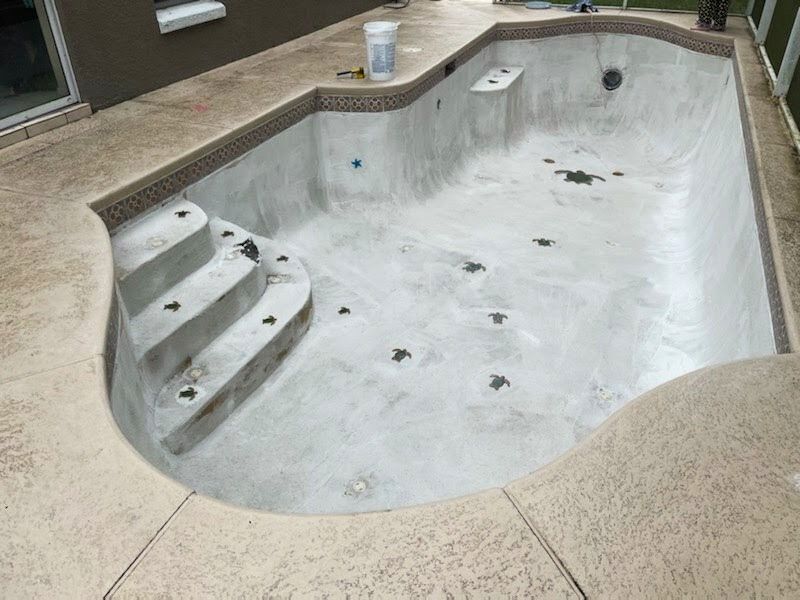 A concrete swimming pool with stairs and a bucket on the side of it.