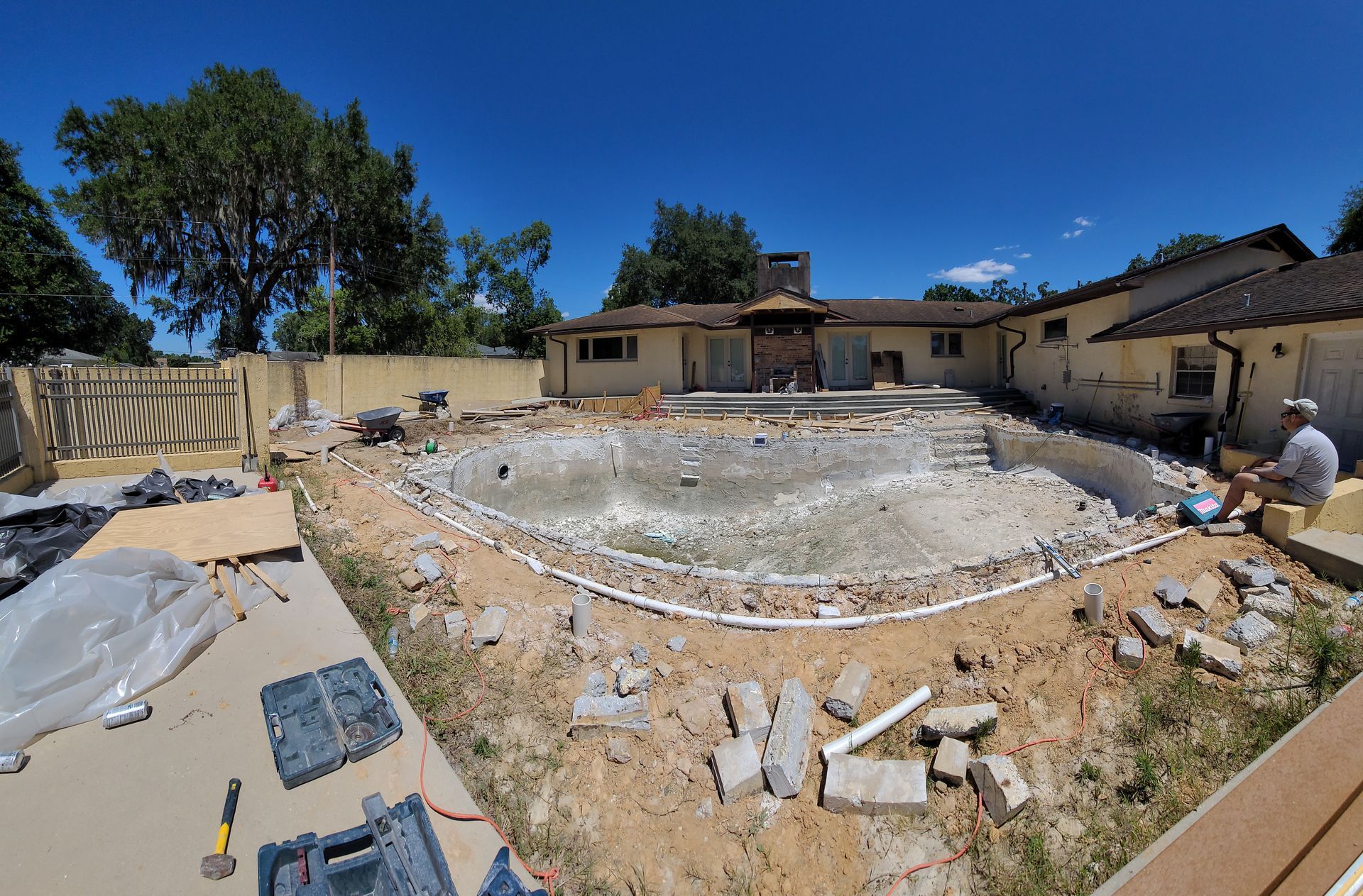 A large swimming pool is being built in the backyard of a house.