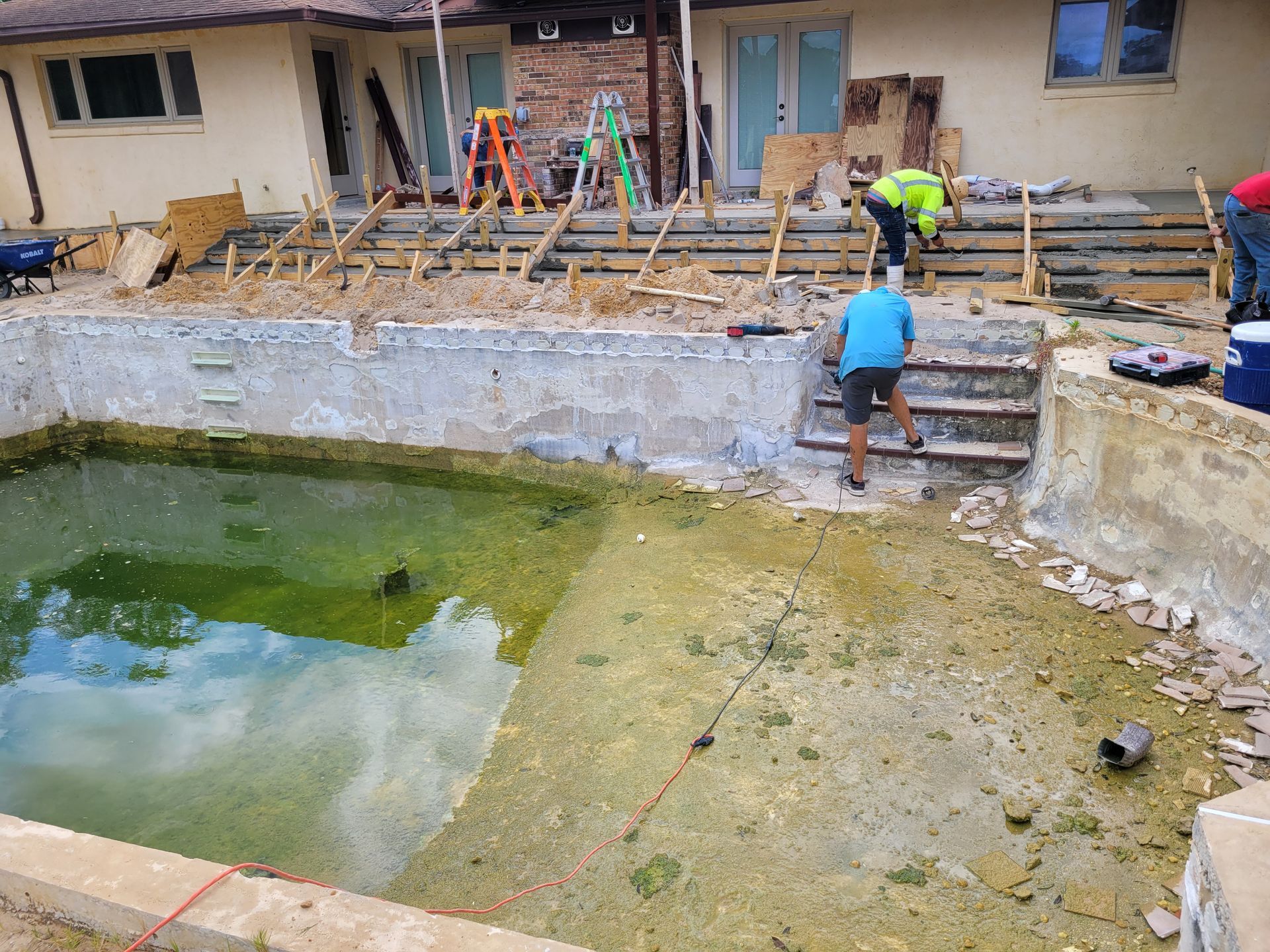 A swimming pool is being remodeled in front of a house.