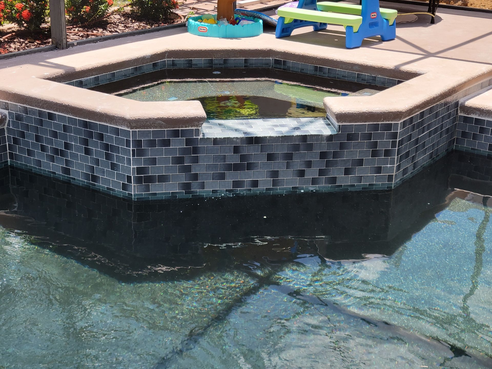 A swimming pool with a hot tub in the middle of it