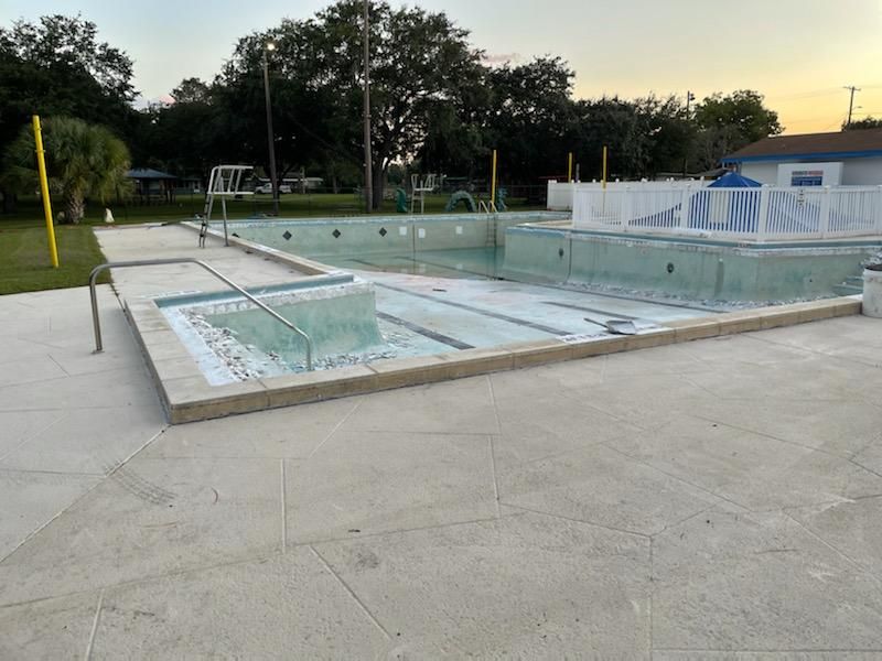 An empty swimming pool with a volleyball net in the background.