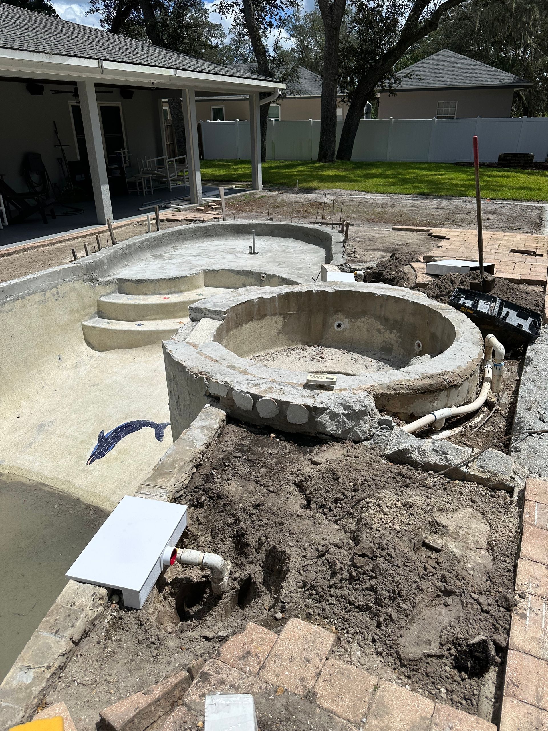 A swimming pool is being built in the backyard of a house.