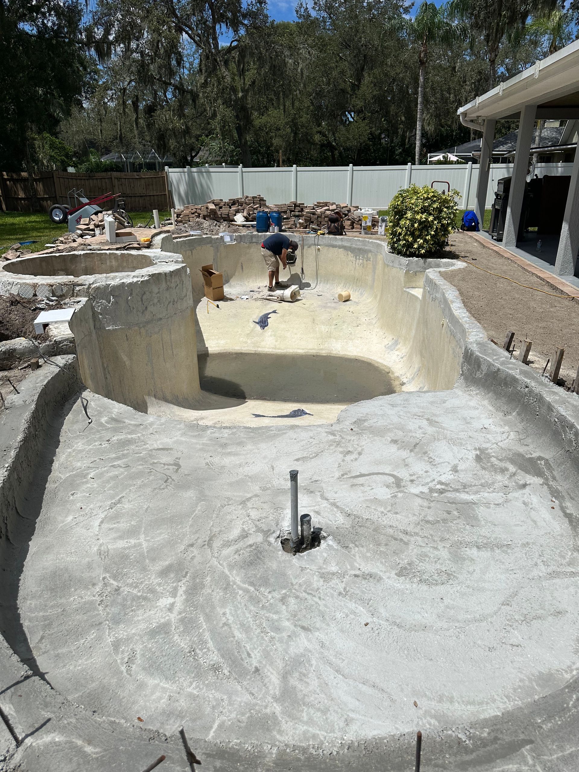 A man is working on a swimming pool in a backyard.