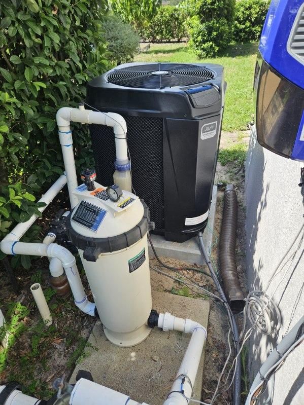 A swimming pool filter is sitting next to a swimming pool heater.