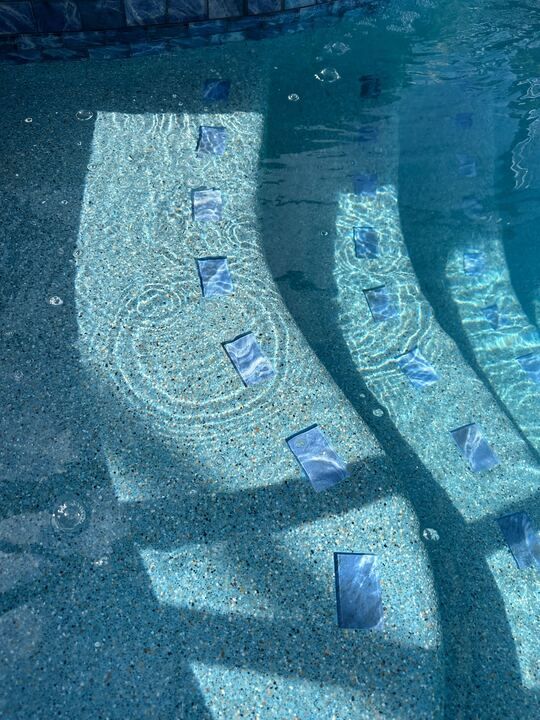 Underwater view of pool steps with blue tile accents.