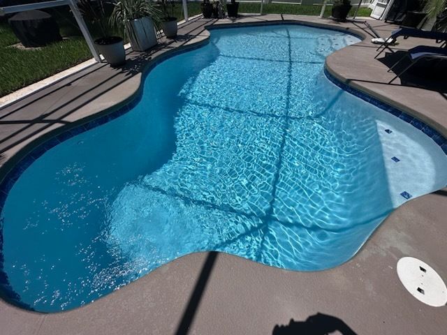Swimming pool with blue water and gray concrete deck.
