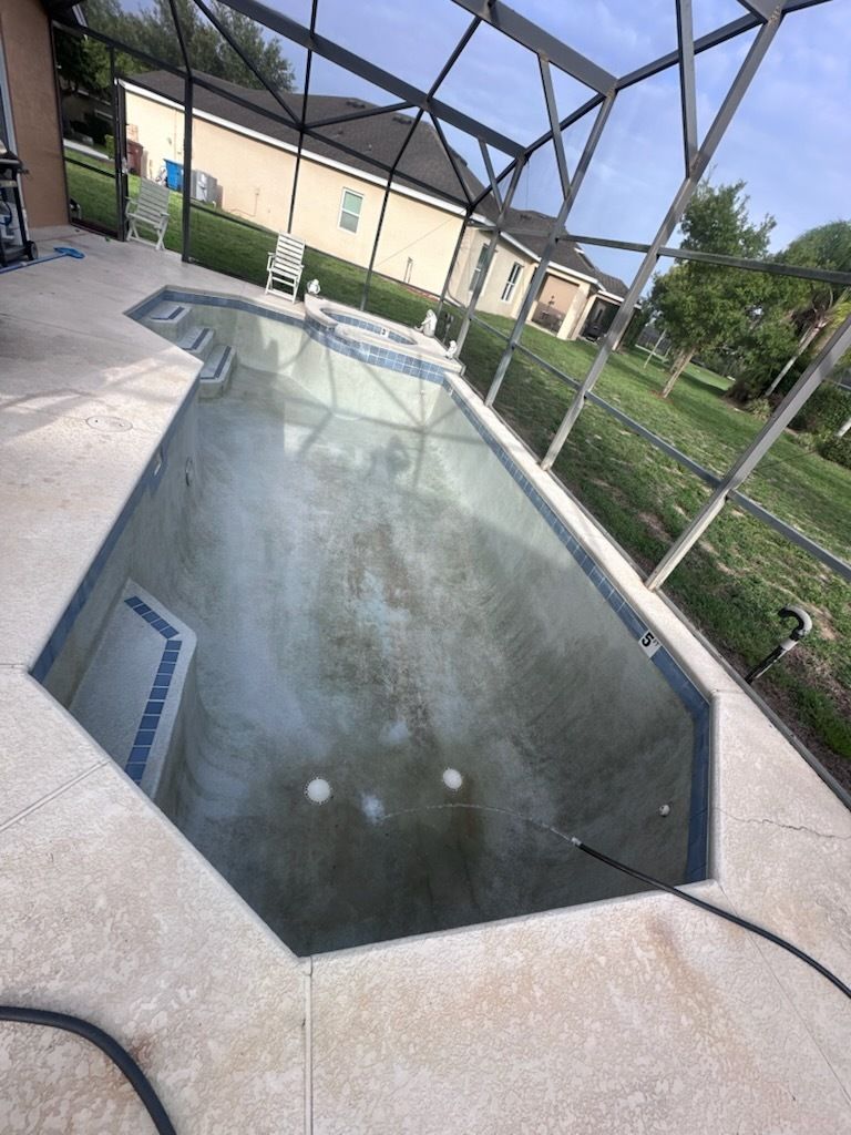 A swimming pool with a screened in area and a house in the background.