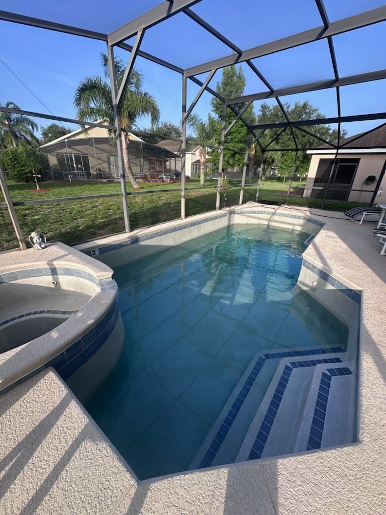 A large swimming pool with stairs leading to it and a hot tub.