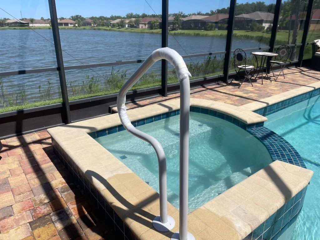 A swimming pool with a hot tub and a view of a lake.