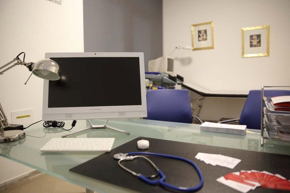 una scrivania con un  monitor, tastiera,mouse e uno stetoscopio