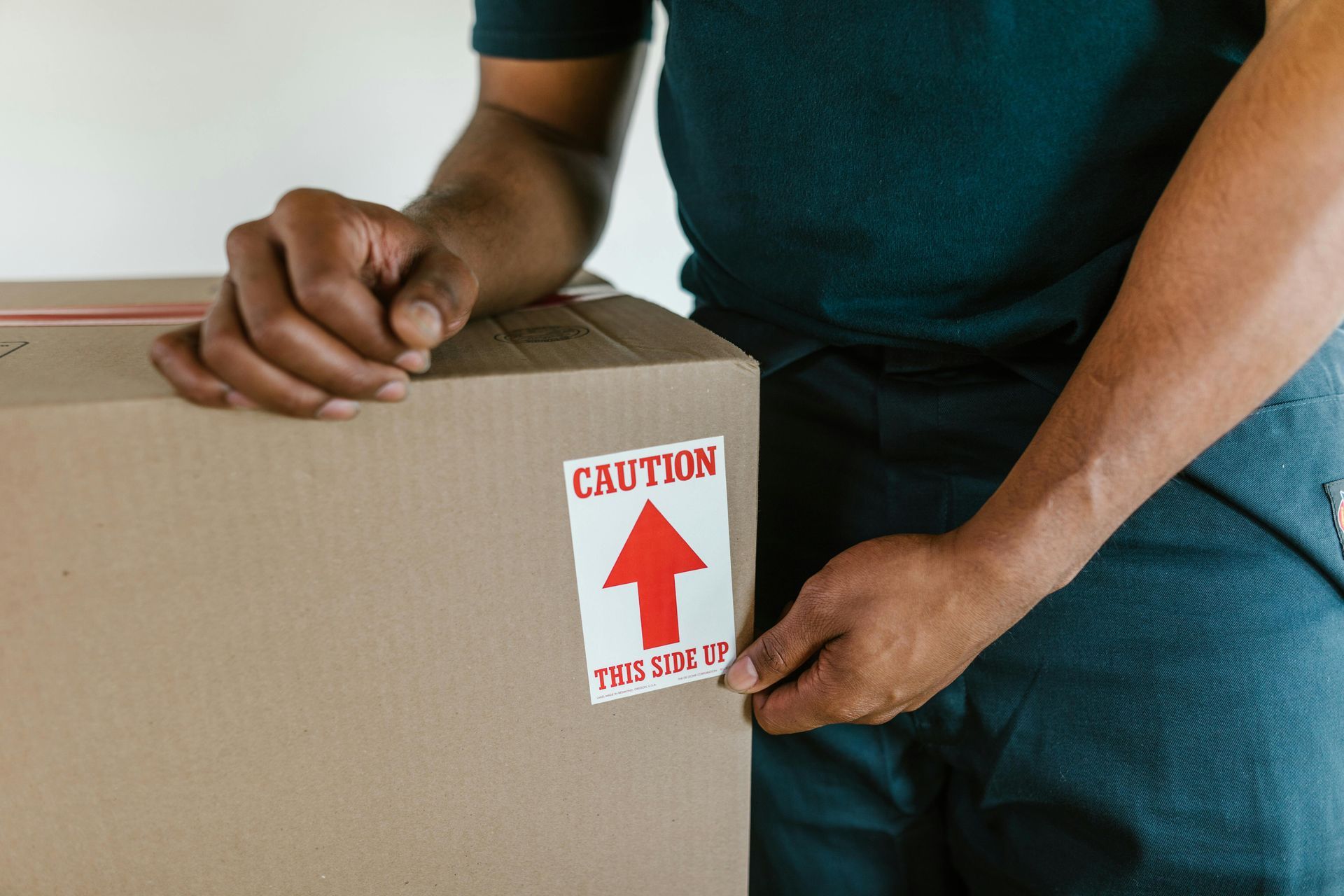 Hands affixing a red caution label to a cardboard box