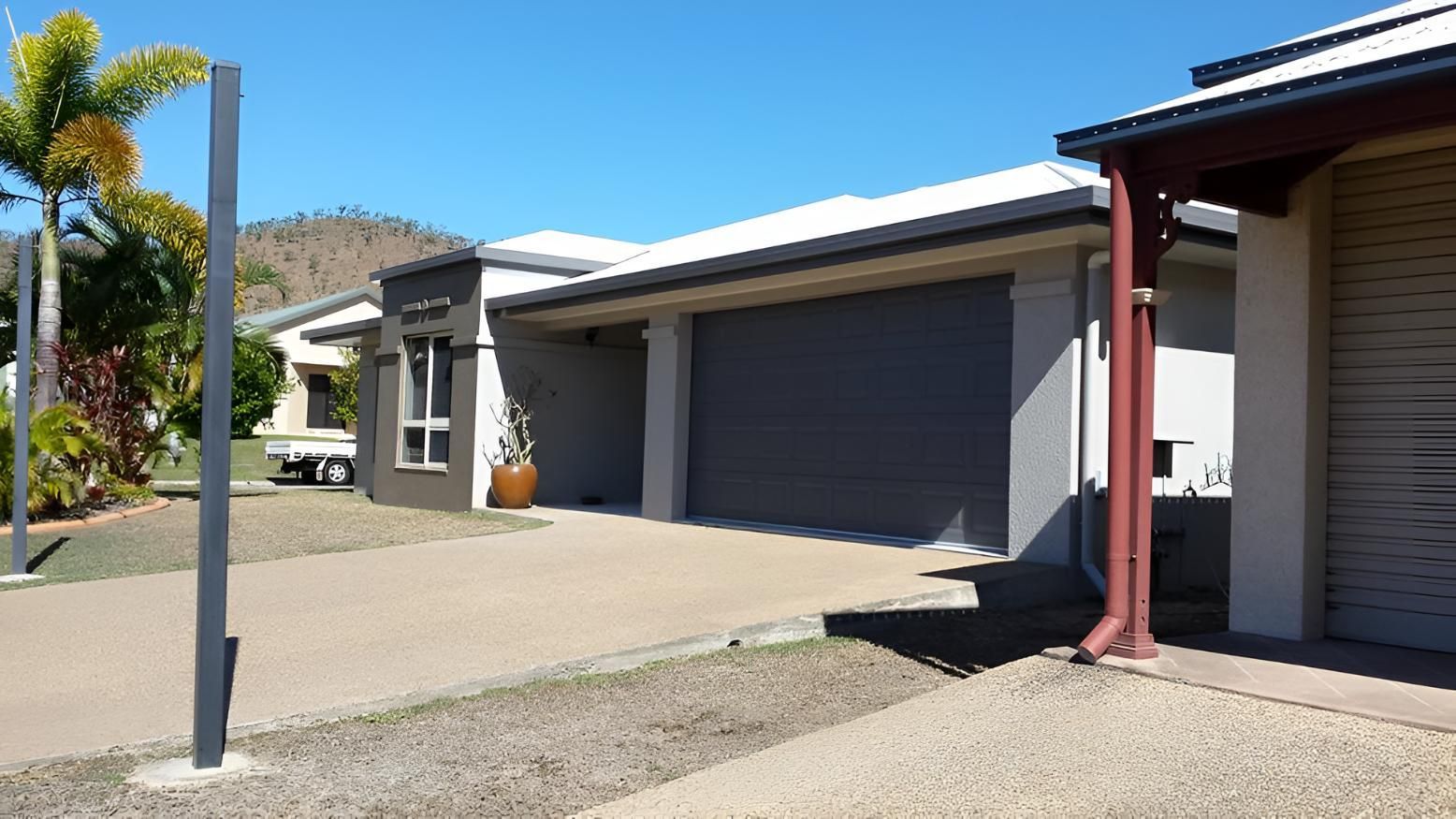A Row Of Houses With Gray Garage Doors And White Roofs — Aaron Lee Painting Pty Ltd In Balgal Beach, QLD