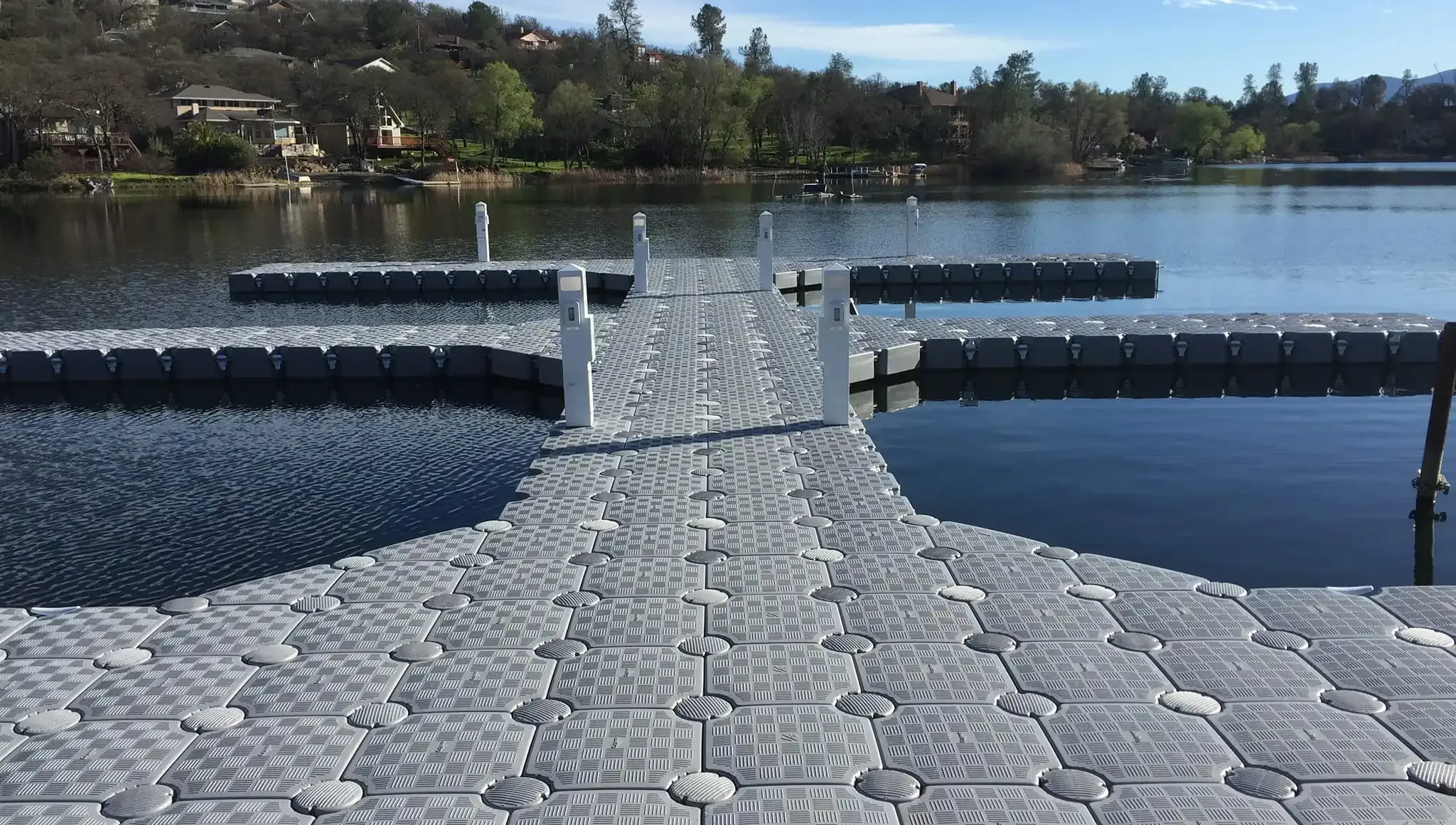 Stone walkway extending over calm water in a reservoir or lake, with wooded shoreline in the distance