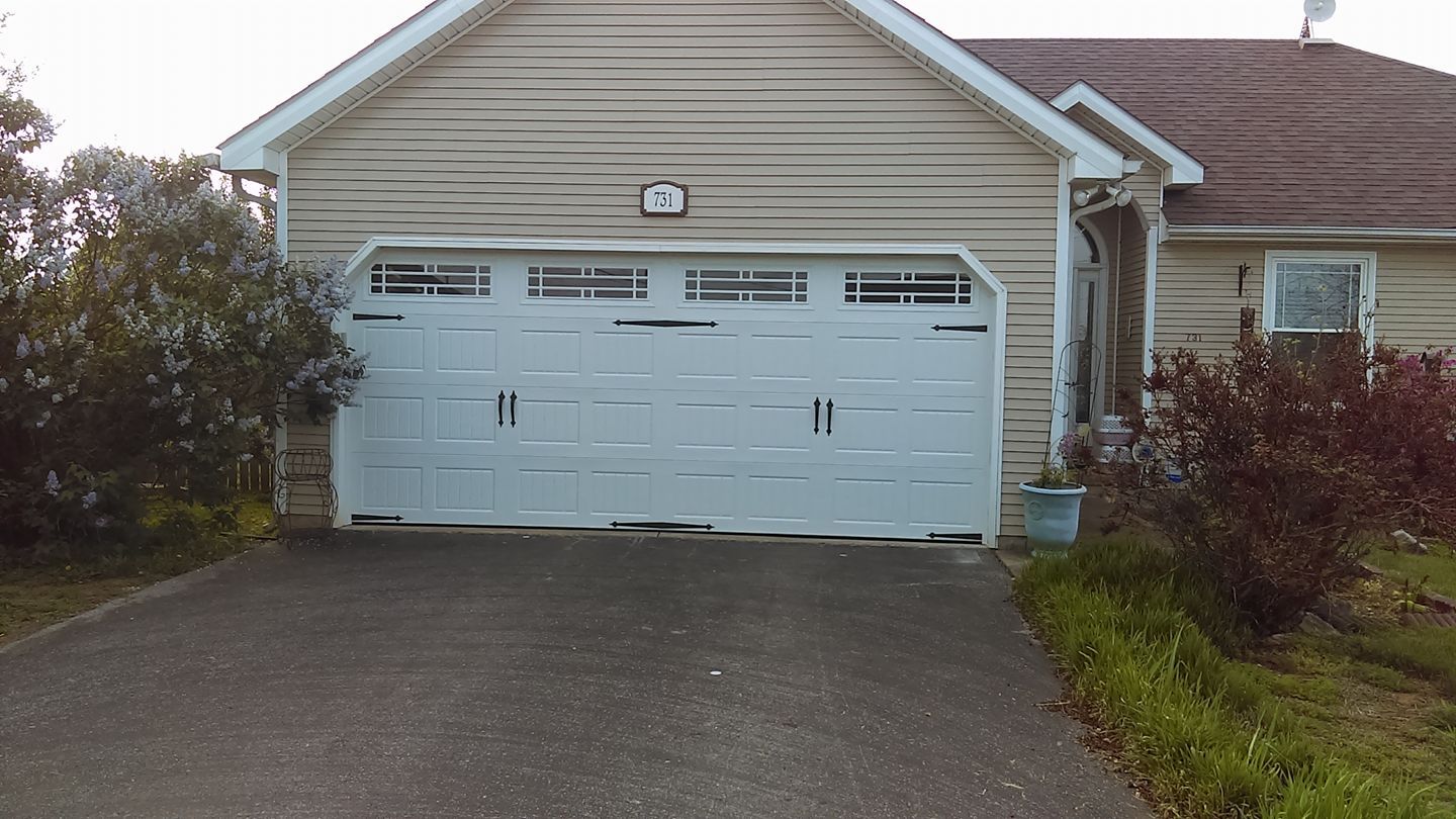 White garage door on a house with beige siding and a driveway.