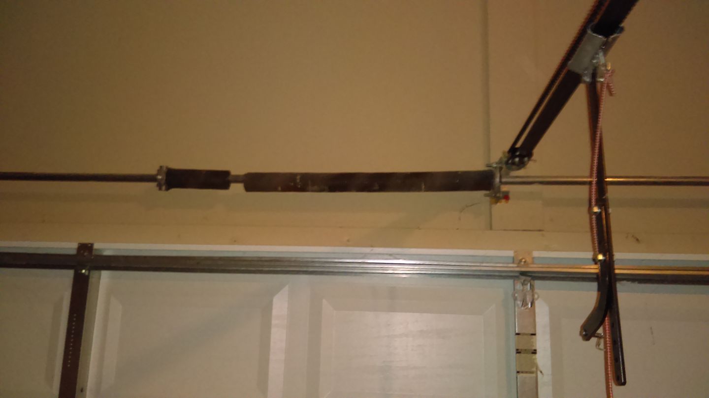 Garage door with torsion spring system, visible above the door. Horizontal, brown spring.