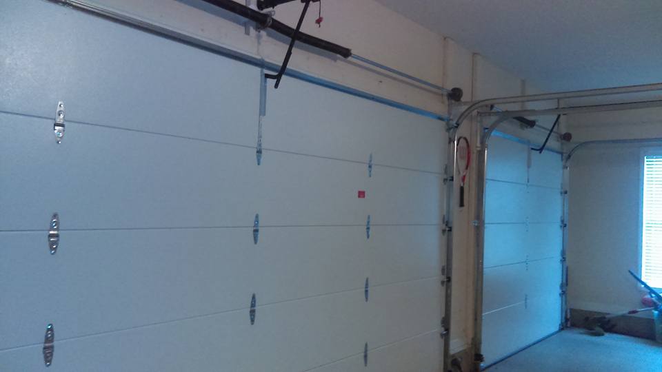 Garage interior with a partially open white door and track system.