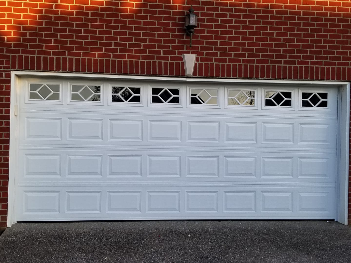 White garage door with geometric top windows on a brick building.