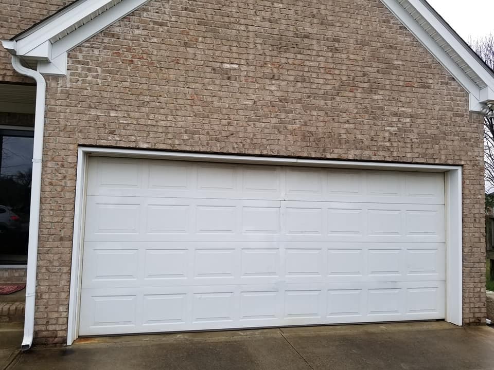 White garage door on a brick house with a gutter on the left side.