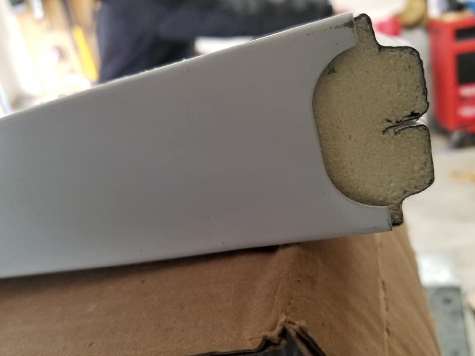 White painted metal frame with exposed foam interior.