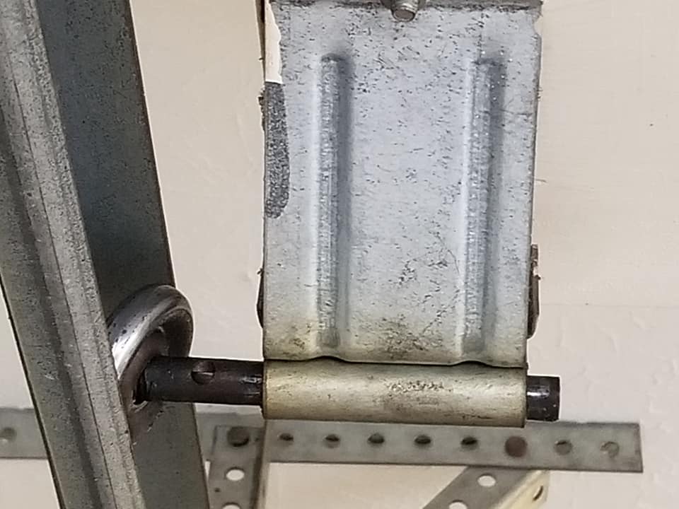 Close-up of a garage door spring system component. Gray metal is mounted to the wall.