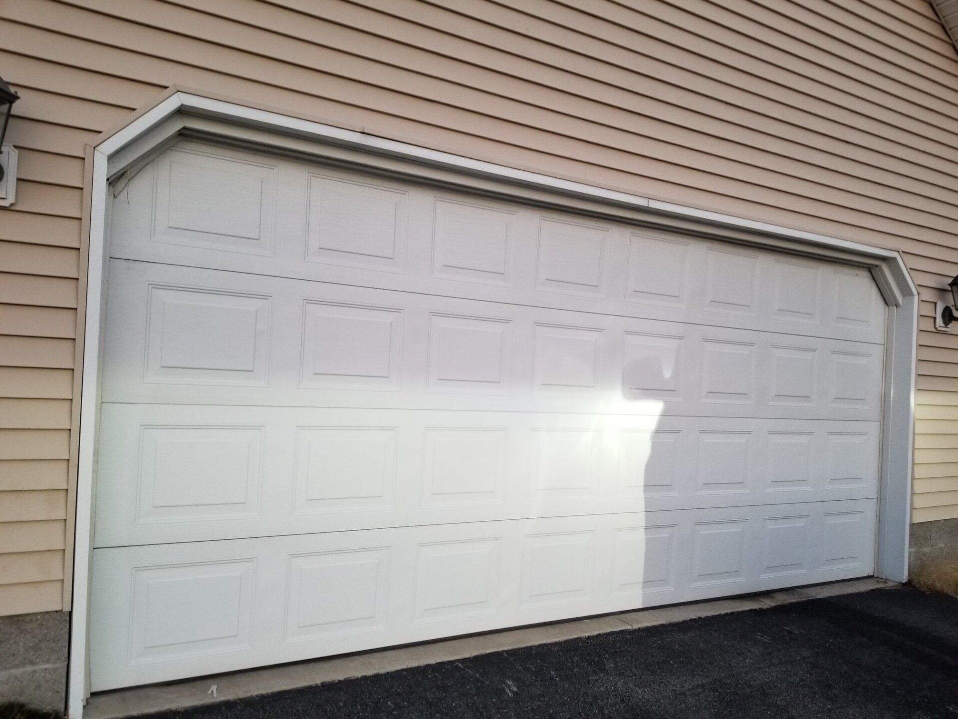White garage door on a tan house with dark asphalt below.
