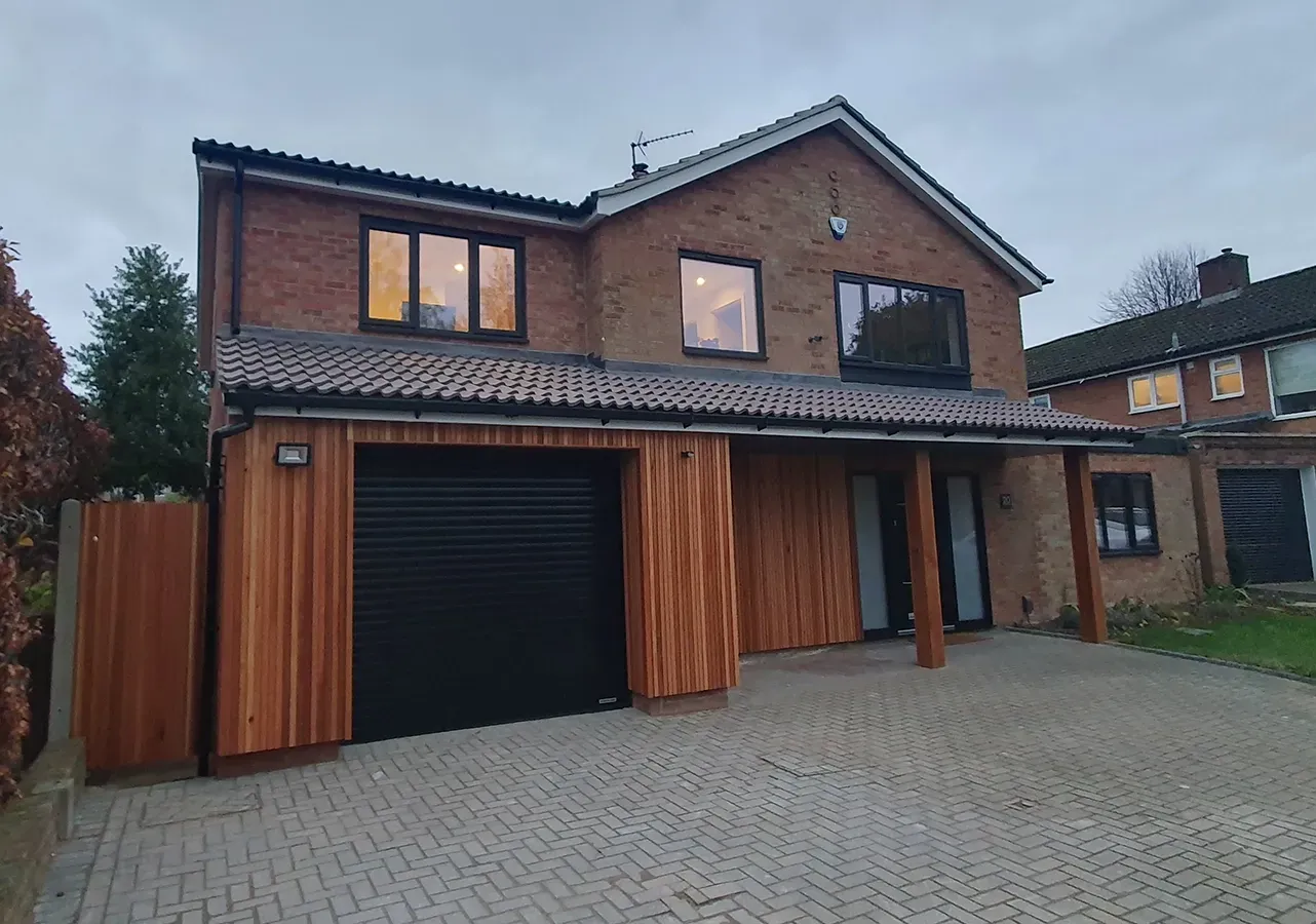 A large brick house with a black garage door and wooden siding.