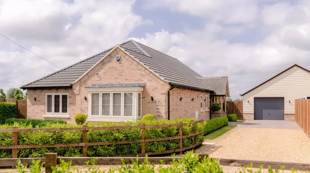 A brick house with a garage and a wooden fence in front of it.
