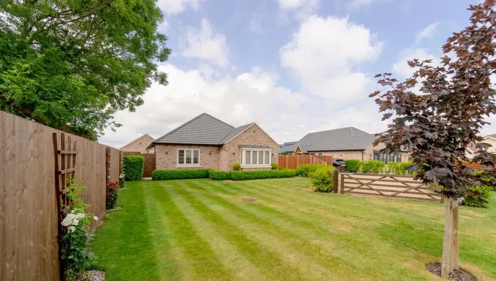 A house with a large lawn in front of it and a wooden fence.