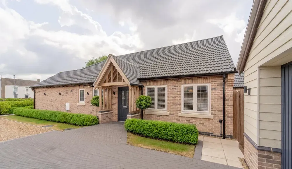 A brick house with a gray roof and a driveway in front of it.