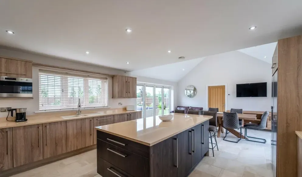 A kitchen with a large island in the middle and a dining room in the background.