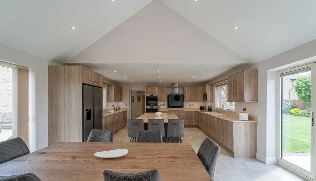 A large kitchen with a wooden table and chairs in it.