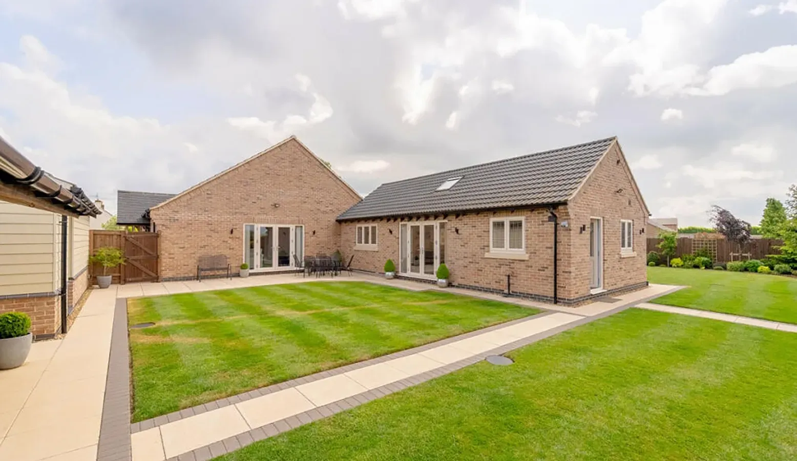 A large brick house with a large lawn in front of it.