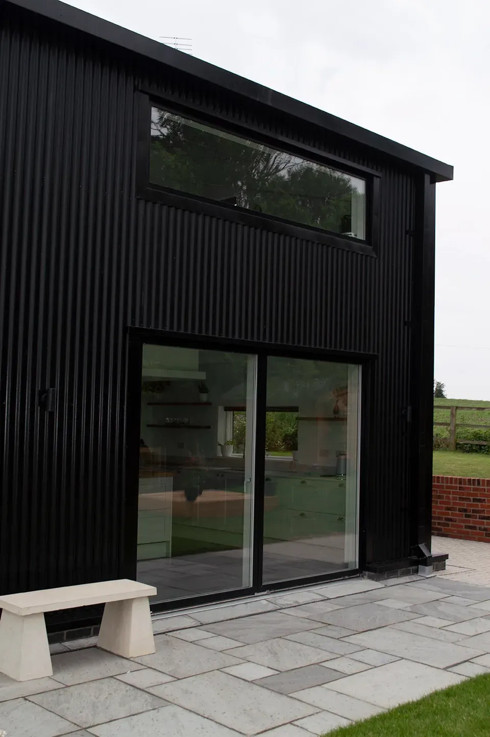 A black house with a sliding glass door and a bench in front of it.