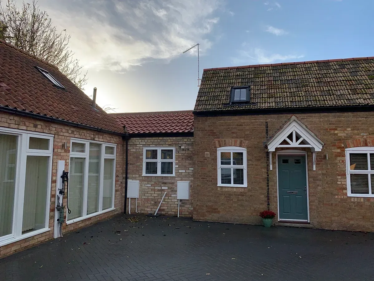 A brick building with a green door and white windows.