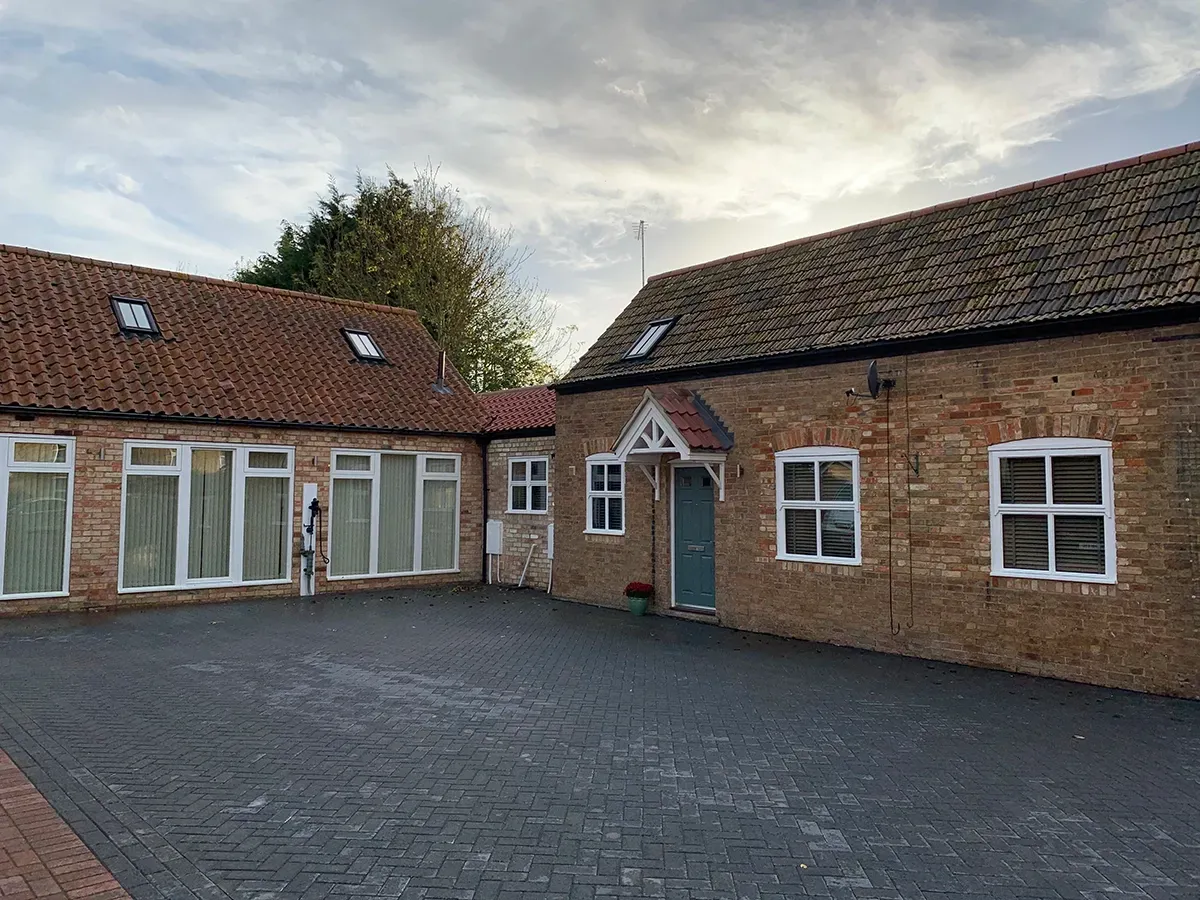A brick building with a lot of windows and a driveway in front of it.