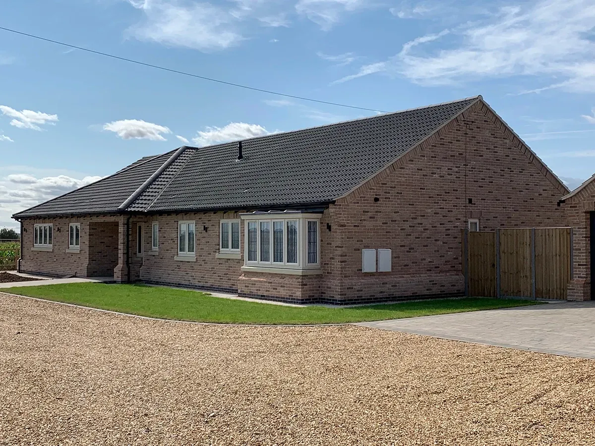 A large brick house with a gravel driveway in front of it.